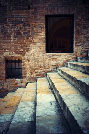 Italy Siena old building closeup with stairs and window on brick wallの写真素材
