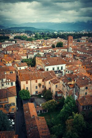 Lucca rooftop view with red roofs of historic buildings and mountain range in Italy.の写真素材