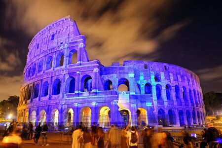 Colosseum at night with tourists and colorful lights, the world known landmark and the symbol of Rome, Italy.の写真素材