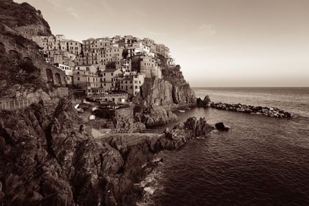 Manarola overlook Mediterranean Sea with buildings over cliff in Cinque Terre, Italy. Black and...
