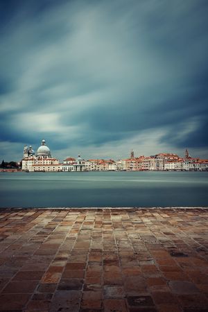 City skyline of Venice with clock tower and dome in long exposure viewed from waterfront in Italy.の写真素材