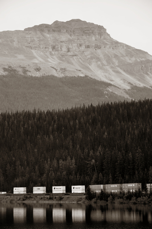 BANFF, CANADA - AUGUST 27: Cargo train lake and mountain on August 27, 2015 in Banff National Park, Canada. Established in 1885, it is the oldest park in Canada.のeditorial素材