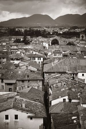 Lucca rooftop view with red roofs of historic buildings and mountain range in Italy.の写真素材