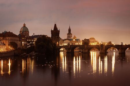 Prague skyline and bridge over river in Czech Republic at night.