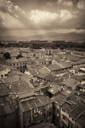 Lucca rooftop view with red roofs of historic buildings and mountain range in Italy.の写真素材