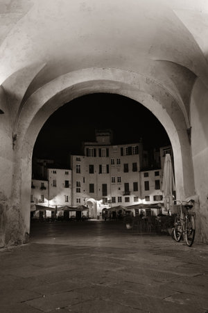 Arch entrance of Piazza dell Anfiteatro in Lucca Italy at nightの写真素材