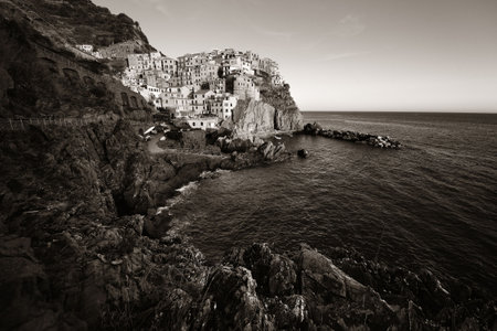 Manarola overlook Mediterranean Sea with buildings over cliff in Cinque Terre, Italy. Black and white.の写真素材