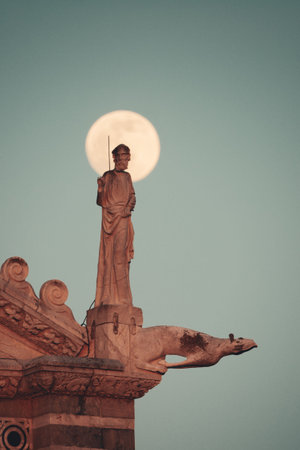 Statue sculpture on roof of cathedral with moon in Piazza dei Miracoli in Pisa Italy.の写真素材