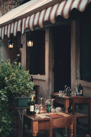 Tables and glass cups waiting for guests in street in Venice, Italy.