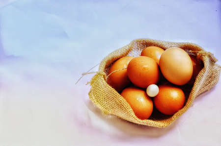 One small white egg was laid together with a pile of chicken eggs in a sack cloth bag , vintage styleの写真素材