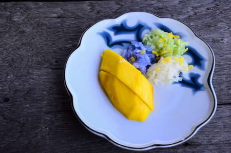 Thai food : Mango sticky rice with coconut milk on wooden floorの写真素材