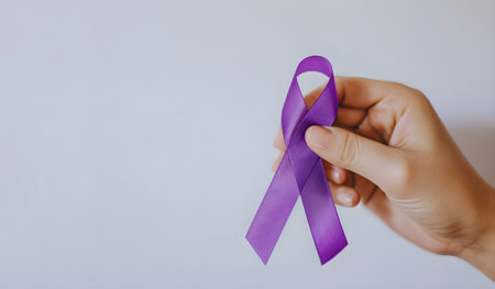 Hand holding purple ribbon on grey background with copy space, Symbols of support in the fight against cancer, World Cancer Dayの素材