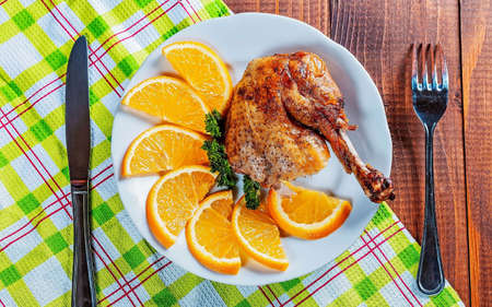 Baked chicken drumstick with orange.in a white bowl on wooden table.の写真素材