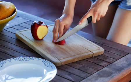 Woman cutting fresh apple at table, closeup shot.の写真素材