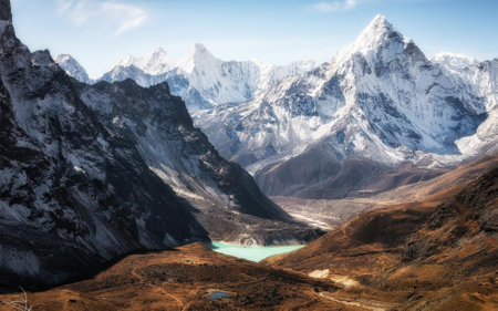 A lake nestled between mountains, with snow-capped peaks in the background. The serene landscape captures the beauty of nature with a clear blue sky above.の写真素材