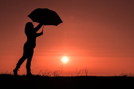 Young girl with an umbrella in the sunsetの写真素材