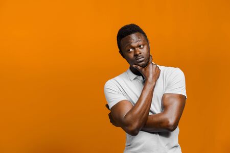 Big discount for our customers. Funny black man points right side and grimacing on orange background. Smiley people lifestyle. Advertise for online delivery services. Empty place for adverの写真素材