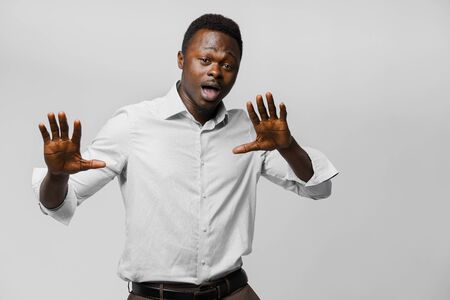 Black african business man dances and opens his mouth. Dark skinned man in white shirt on white background. Advert for online deliveryの写真素材