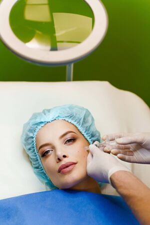 Filler injection of hyaluronic acid. Contour plastic for correcting the volume and shape of the nose, chin, cheekbones, temples. Cosmetic rejuvenating facial treatment in medical clinicの写真素材