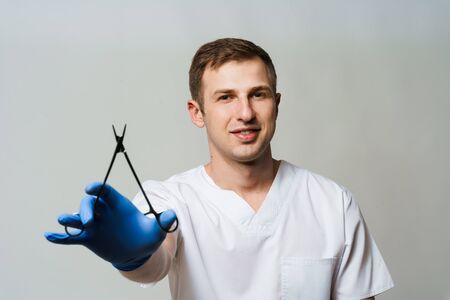 Doctor surgeon with needle holder in medical gloves on white background. Plastic surgery advertの写真素材
