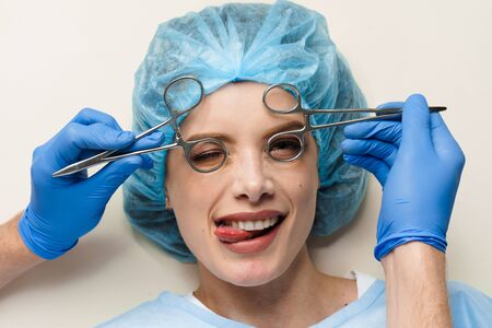 Funny consultation with jokes of plastic surgeon in medical center. Doctor man in mask asks girl patient about injections on the lips, chin, forehead. Wrinkle removalの写真素材
