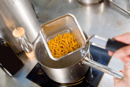 Boiled noodles are gets out from pan. Chef cooks spaghetti noodles for ramen soup. Cooking ramen soup with meat, mushrooms, radish, eggs.の写真素材