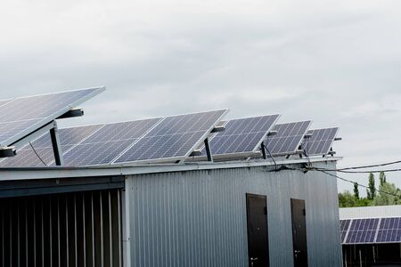 Solar panels stands in row on the roof . Free electricity for home. Sustainability of planet. Green energy. Solar cells power plant business. Ecological clean energy. Blue panels on the ground.の写真素材