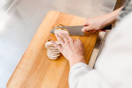 Raw fillet of chicken on cutting board. Cut fillet for ramen soup on kitchen . Chef cooks meat with...
