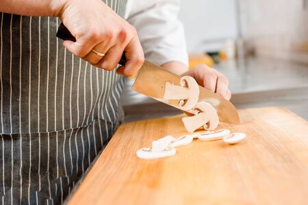 Cut white mushrooms for ramen soup on kitchen . Chef cooks white mushrooms with knife in restaurant. Cutting white mushroomsの写真素材