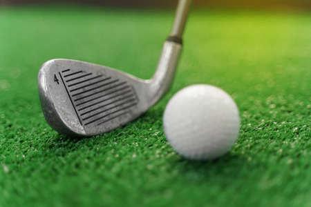 Close-up niblick and white ball for golf on the green grass. Empty right side for text of advert for golf clubs. Playing in golfの写真素材