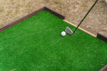 Golf sport game with niblick and white ball on the green grass. Playing in mini-golf. Empty place...
