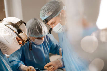 Surgeon with headlamp and scissors do plastic operation in medical clinic. Chest augmentation plastic operation and correction in medical clinicの写真素材