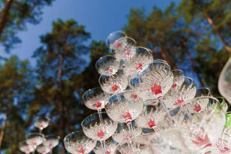 Big pyramid of glasses with champagne and red cherry inside on business meeting at summer day in the forest. Drink coctkail catering for weddingの写真素材