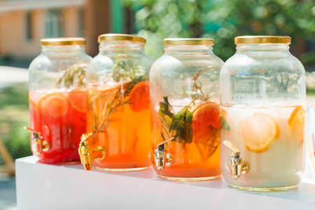 4 lemonade dispensers with fruits: grapefruit, orange, lemon. Welcome zone of drinks with colorful...