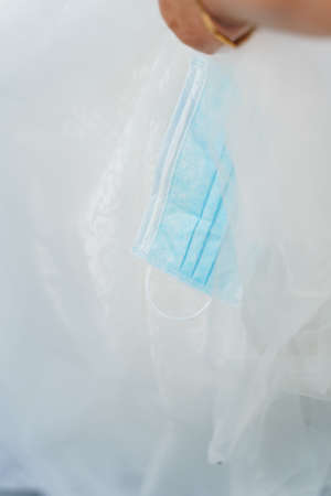 Medical mask and wedding dress close up. Blue surgical mask on the white background