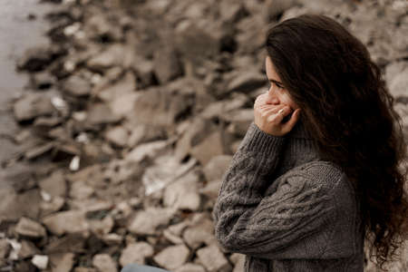 Girl with curly hair on the background of birch with stones and lake in autumnの写真素材