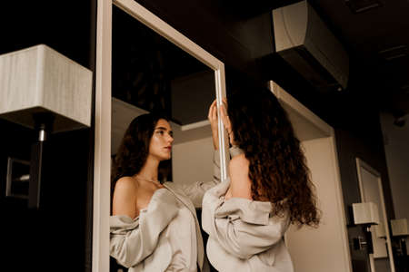 Young woman is looking at her reflection in the mirror. Perfect skin. Sexy model and her reflection...