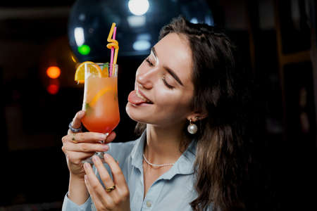 Girl with cocktail is drinking in night club before party. Advert for bar and night clubs. Citrus...