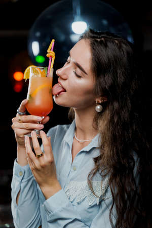 Girl with cocktail is drinking in night club before party. Advert for bar and night clubs. Citrus...