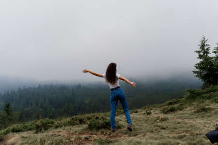 Girl is traveling in the mountains. Foggy day. Hiking and climbing up to the peak of the mountain....