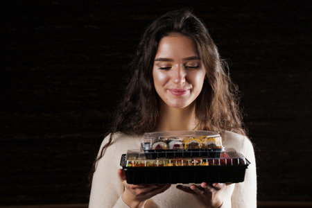 Sushi set in box healthy food delivery service. Girl courier with 2 sushi boxes. Japanese cuisine:...