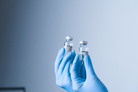 2 doses of coronavirus vaccine. Close-up covid-19 Vaccination. Woman in blue medical gloves holding...