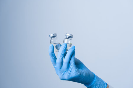 2 doses of coronavirus vaccine. Close-up covid-19 Vaccination. Woman in blue medical gloves holding...