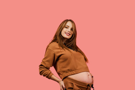 Pregnant woman in oversized suit on a pink background. Pregnancy. Expectation of the child....