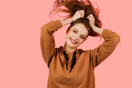Life style. Inspired and happy woman smiles, laughs and grimaces on pink background. Model posing in a photo studio. Girl weared brown oversize costumeの写真素材