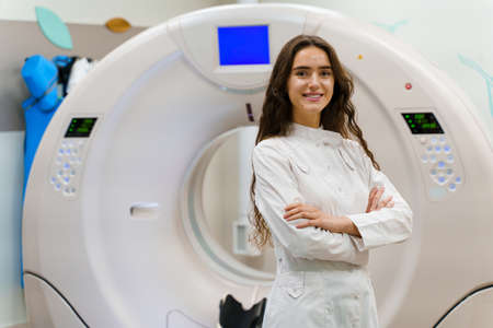 The young women doctor in medical gown looks in camera. Patient after computer tomography. CT...