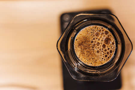 Coffee aeropress creams close-up. Alternative coffee brewing method. Aeropress device on the table. Advert for social networks of restaurants, cafe.の写真素材