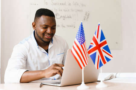 Black handsome man uses his laptop for online work according social distancing. Speaking by web camera with colleagues. Scientist works at home on quarantine period.の写真素材