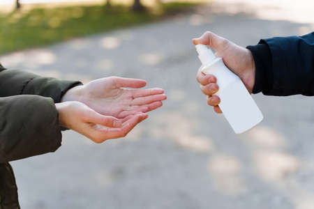 Girl cleans her hands with sprey antiseptic. Disinfection to hands for stop pandemic of virusの写真素材