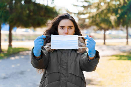 Caucasian girl shows sterile medical mask. Blue medical gloves. Protection from coronavirus covid 19